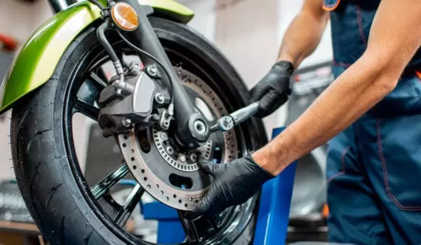 Mécanicien procédant au changement d'un disque de frein d'une moto